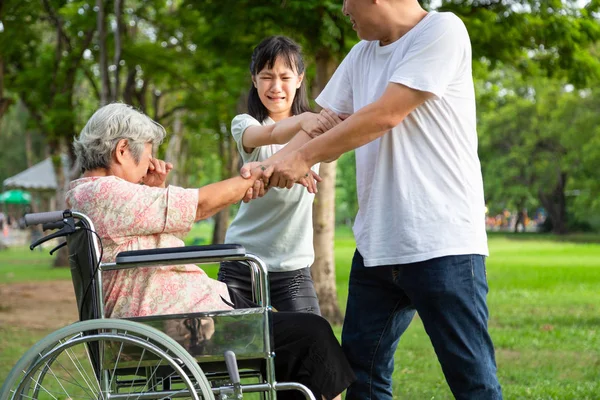 Азиатская пожилая женщина в инвалидной коляске подвергалась физическому насилию, нападениям на открытом воздухе, прекращению физического насилия над пожилыми людьми, сердитым мужчиной или сиделкой, прекращению насилия в семье и концепции агрессии — стоковое фото