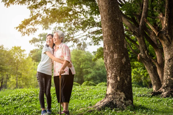 Feliz asiática niña pequeña apoyo, abrazar abuela mayor, nieta sonriente en el parque al aire libre, anciana con bastón, caminar ejercicio para la salud en la naturaleza, cuidado de la salud familiar, concepto de amor — Foto de Stock