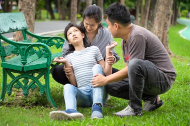 Sick little child girl with epileptic seizures in outdoor park,daughter suffering from seizures,illness with epilepsy during seizure attack,asian mother,father care of girl patient,brain,nervous system concept clipart