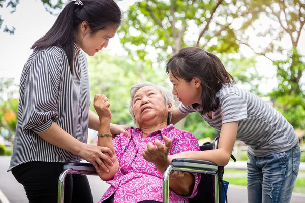 Sick senior grandmother in wheelchair with epileptic seizures in outdoor,elderly patient convulsions suffering from illness with epilepsy during seizure attack,asian daughter,granddaughter crying,family care concept — 스톡 사진