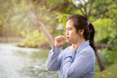Hasta kadın boğaz ağrısı kötü acı hissi, ağrılı yutma, asya kadın hasta öksürük var, tahriş ve boğaz ağrısı, açık parkta boynunda el tutarak, iltihap, bakteriyel enfeksiyonlar hastalıklar, alerji, sağlık