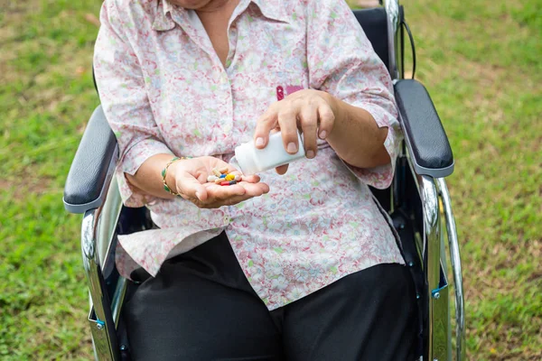 Asian senior woman medicine pills or capsules in hand,sick female patient taking,eating vitamin,antibiotic,painkiller,nutritional supplements,elderly people hand pouring pills for the pain from bottle,health care,medicine concept — Stockfoto