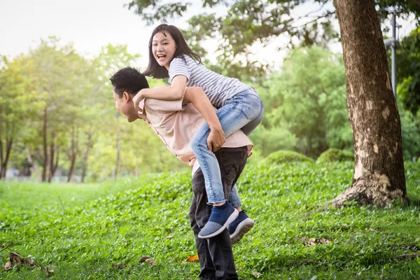 Felice padre asiatico ridere dando cavalcata a bella figlia divertirsi, abbraccio insieme, sorridente bambina godendo gioco attivo con papà, giovane uomo che trasporta la figlia carina sul retro, giocando nel parco all'aperto — Foto Stock