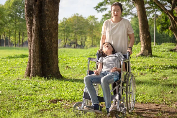 Menina criança doente com paralisia cerebral em cadeira de rodas parque ao ar livre ou filha sofrendo de convulsões, doença com epilepsia, mãe asiática ou cuidador cuidado de paciente menina, cérebro, conceito de deficiência intelectual — Fotografia de Stock