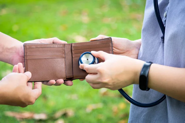 Hands checking open wallet with stethoscope in green nature,care of money problems,financial health care,money saving for medical care expenses,health insurance,economic depression,financial crisis,frugal,life planning concept — Stock Photo, Image