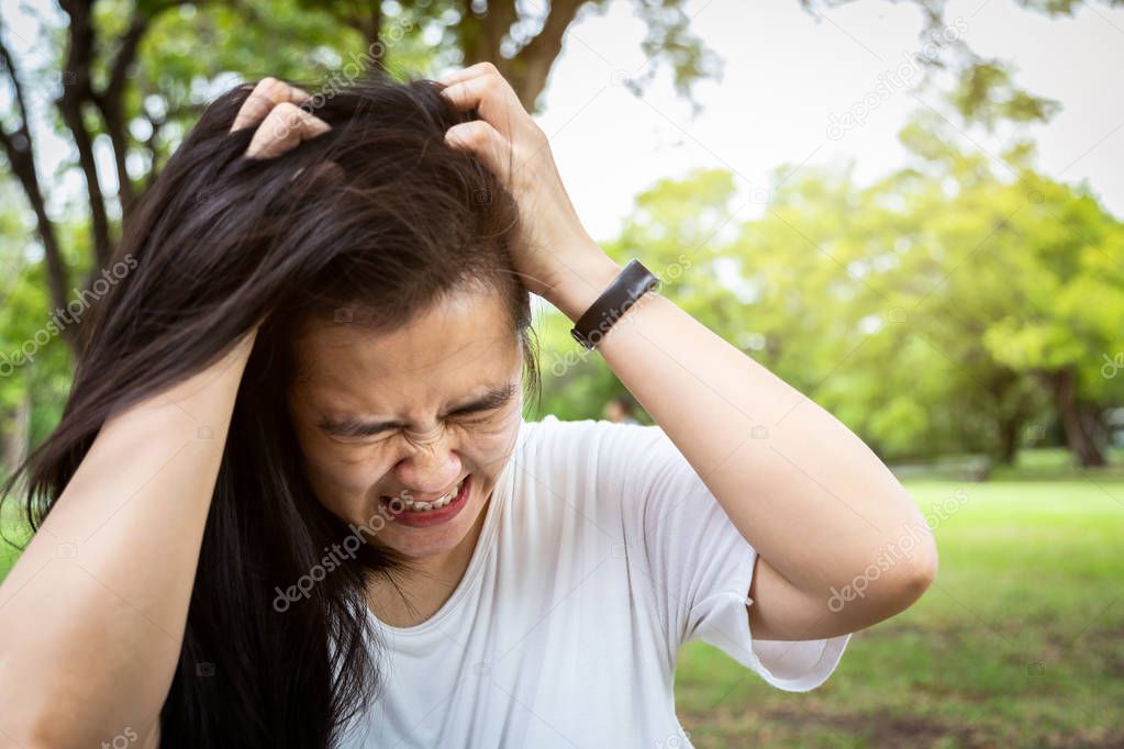 Sick asian young woman suffering from headache,depression having nervous breakdown,mental health disorder or bipolar pulling her hair in crazy stress,unhappy person problem was stressed and hurt herself in outdoor park