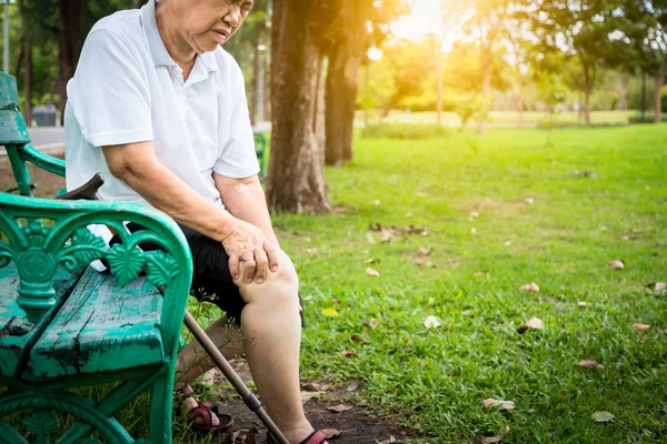 Азійська старша жінка артрит, остеоартрит, літні люди сидять, тримаючи за руку коліна в парку, відчувають біль у коліні, опухлі коліна, біль у ногах після ходьби, проблеми зі здоров'ям, концепцію медичного обслуговування. — стокове фото