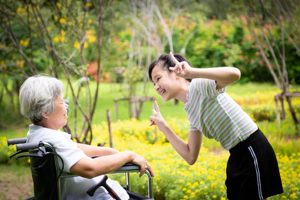 Щаслива азіатська літня жінка дивиться смішна дівчинка грає або танцює, усміхнена онука, старша бабуся насолоджується разом на відкритому повітрі квітка поцілунок для деякого свіжого повітря, сім'ї, мульти покоління концепції — стокове фото