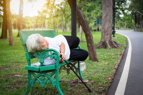老年痴呆症老年妇女与时间或地点的混淆，与年龄有关的记忆力丧失，患痴呆症或无家可归的妇女睡在室外公园的长椅上，老年痴呆症 — 图库照片