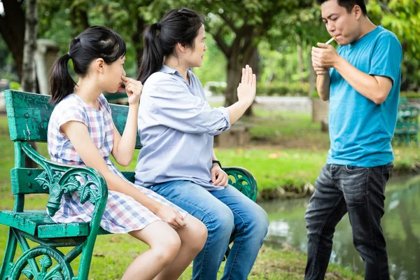 Cesser de fumer des cigarettes, mode de vie malsain, cesser de fumer, mari asiatique tenant la cigarette dans les mains près des personnes dans la famille, fille et femme couvrant le visage pollution olfactive, non fumeur, concept de soins de santé — Photo