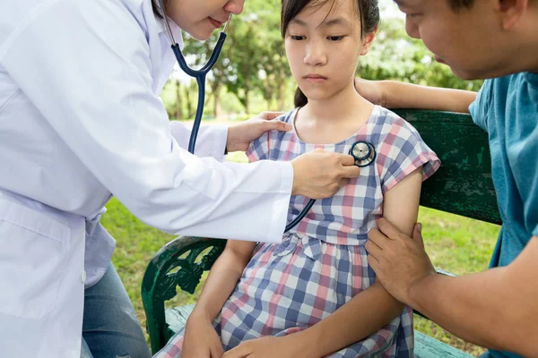 Женщина азиатский врач или мать осматривая дочь ребенка девочка пациентка по стетоскопу, семейный врач проверка с помощью стетоскопа для прослушивания дыхание на открытом воздухе в больнице, общий осмотр здоровья, медицинская концепция — стоковое фото