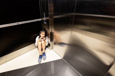 Anxiety asian child girl having panic disease attack in an elevator,stressful depressed teenage girl with mental health illness and narrow fears,suffocation, heart palpitation suffer from panic disorder  clipart