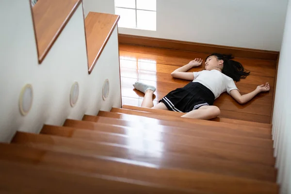 Asiatisk barnflicka i koma på golvet känsla medvetslös efter olycka, faller ner från trappan, sjuk kvinnlig tonåring föll eller halkade till golvet på grund av yrsel, svimma, lider av sjukdom, farlig situation hemma — Stockfoto
