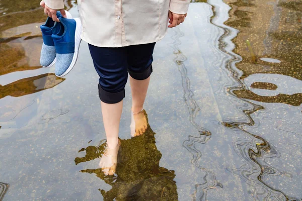 Žena kráčí po povodňové cestě s podkovy po silných deštích, příčinou svědění kůže patří, pozor na leptospirózu, to může být infikován kontaktem s vodou, sportovci nohy nebo tinea pedis — Stock fotografie