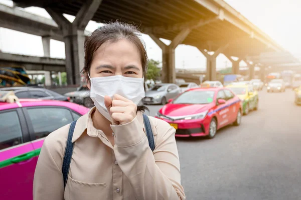 Asijská mladá žena trpí kašel s obličejovou maskou, nemocní lidé nosí lékařskou masku z důvodu znečištění ovzduší na ulici, špatný zápach, znečištěný vzduch, koncepce znečištění, prašné alergie, zdravotní péče — Stock fotografie