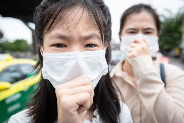 Asian daughter child girl,mother suffer from cough,sick people  wearing face mask protection because of air pollution in the city,allergy to dust,dirty air prevent PM 2.5,healthcare,respiratory disease