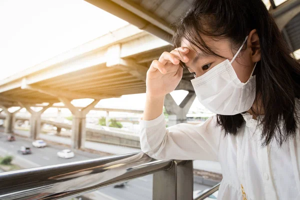 Niña asiática sufren de dolor de cabeza con el clima es muy caliente y la contaminación del aire, la alergia al polvo, se sienten enfermos, mareados, desmayos, las personas que usan protección mascarilla porque el aire sucio previene PM 2.5 — Foto de Stock