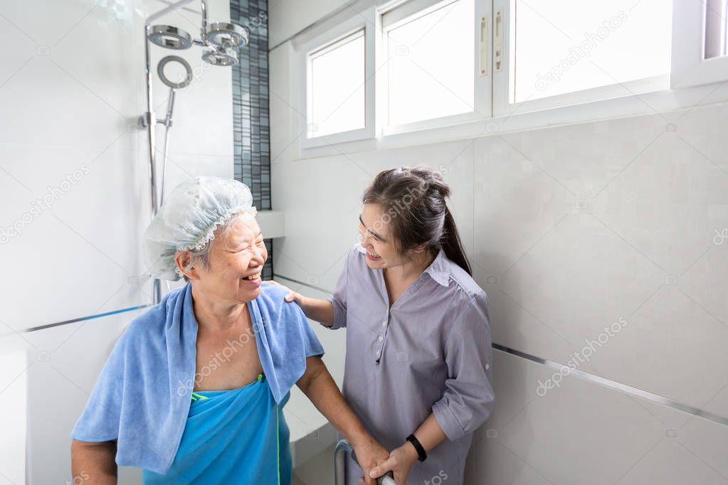 Asian daughter or female care assistant service,help,support senior woman taking a shower in bathroom,take care closely,happy mother is difficult to help herself,concerned about the safety and accidents of elderly people at home