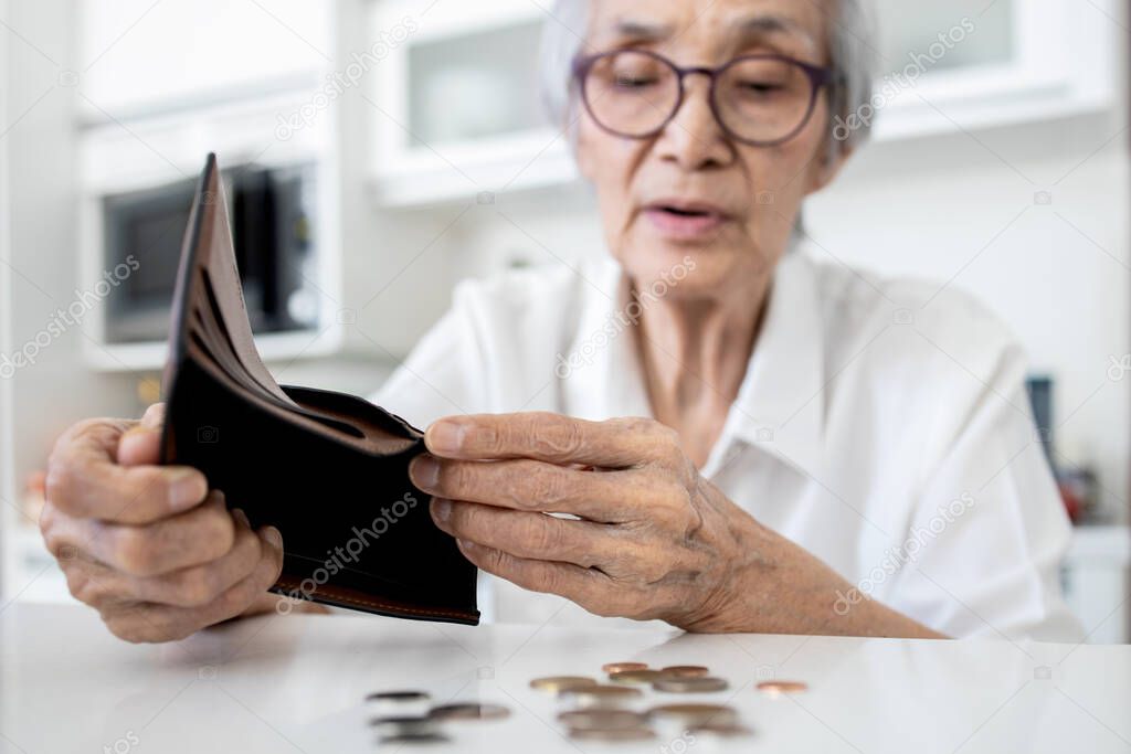 Female senior holding empty wallet,old people shaking out money coins in wallet,financial problems in the retirement age of elderly,planning savings,poverty during Coronavirus crisis,economic downturn