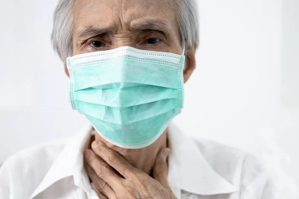 Sick senior in protective mask,old people has sore throat,cough,fever and phlegm in the throat,illness symptom of COVID-19 infection,elderly woman wear face mask to prevent the spread of Coronavirus