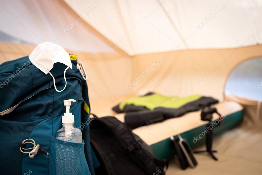 Vacation travel,holiday trip in new normal concept,medical protective mask,alcohol antiseptic gel on a backpack in the tent,hand sanitizer for cleaning hand to prevent Coronavirus,COVID-19,health care