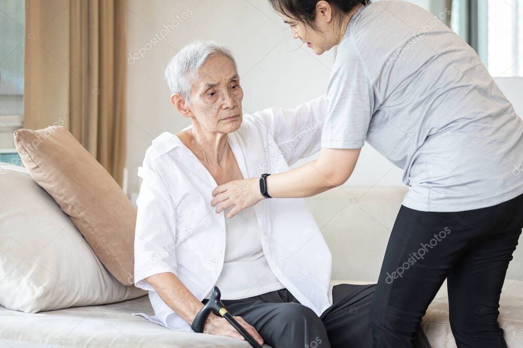 Asian daughter in charge is helping to dress up,chang clothes for a helpless old patient,taking care of senior mother suffer from stroke,lacking strength,decrepit of person,elderly woman and infirm