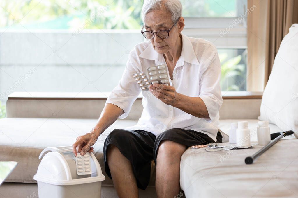 Elderly people is checking expiration date or deterioration of medication before use in the treatment,senior woman reading pill label before taking of medicine and throwing expired drug into the trash