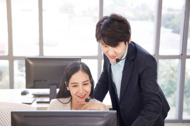 İki Asyalı çağrı merkezi operatörü birlikte çalışıyor ve birbirlerine yardım ediyorlar. İş, takım çalışması, ofis hayatı kavramı.