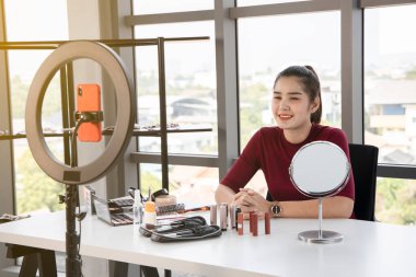Güzel Asyalı etkileyiciler çeşitli kozmetik ürünlerini gözden geçirirler. Her gün makyaj yaptığı bir kadın var..