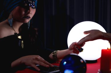 Falcı, dijital tablet kullanarak müşterinin geleceğini ya da kaderini tahmin etmek için avuç içini okur.