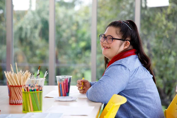 ダウン症候群の幸せなアジアの女の子は学校でアートクラスで勉強しています 学校で学ぶ障害児の概念 — ストック写真