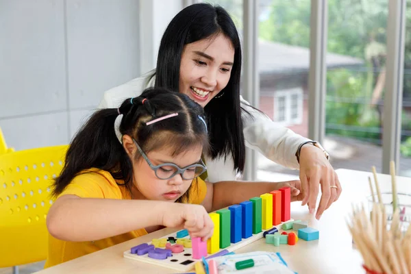 アジアの女の子とともにダウンの症候群遊びパズルおもちゃとともに彼女の先生で教室 — ストック写真