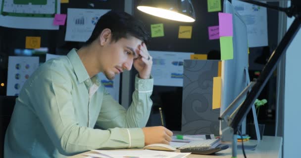 Empresario sobrecargado trabajando hasta tarde en la oficina . — Vídeo de stock