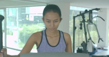 Asyalı kızı spor salonunda eliptik makinede kardiyo egzersiz.