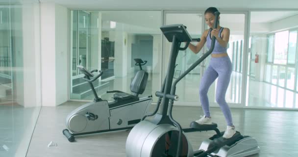Asiatique fille exercice cardio sur la machine elliptique dans la salle de gym . — Video