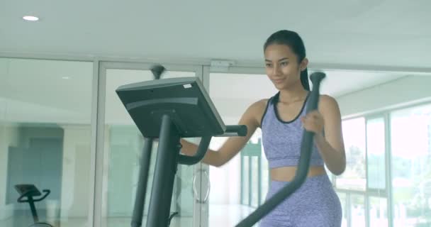 Asiatique fille exercice cardio sur la machine elliptique dans la salle de gym . — Video