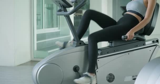 Ženy asijské sportovní jízda na stacionárním kole v tělocvičně. — Stock video