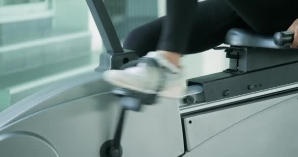 Asiatique sport femmes équitation un stationnaire vélo dans la salle de gym . — Video