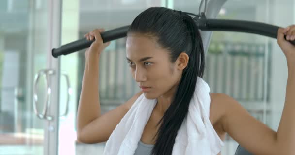 Chica asiática culturista usando una máquina de pesos en el gimnasio . — Vídeo de stock