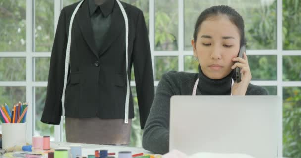 Hermosa mujer diseñadora de moda sentada en su escritorio hablando por teléfono — Vídeos de Stock