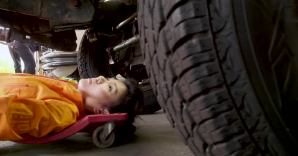 Genç güzel araba tamircisi tamir için arabanın altına yatıyor. — Stok video