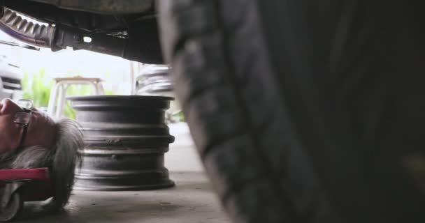 Berufsmechaniker liegt unter dem Auto, um es zu reparieren. — Stockvideo
