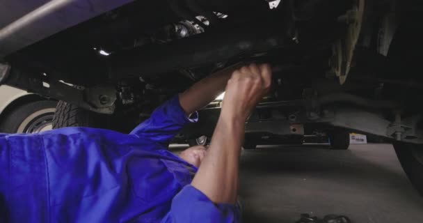 Mecánico de hombres profesionales está mintiendo debajo del coche para repararlo . — Vídeos de Stock