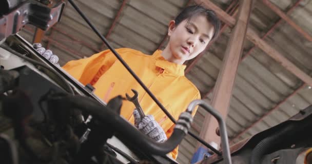 Jonge mooie auto monteur reparatie van een auto in een garage. — Stockvideo