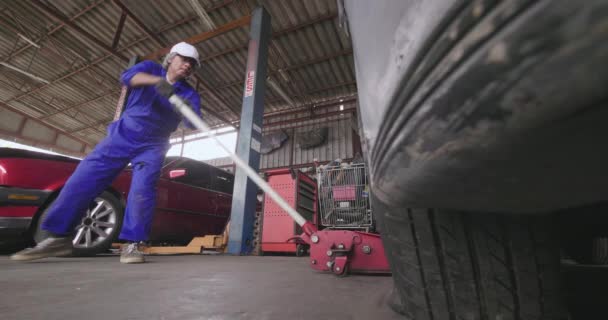 Mécanicien réparateur monter une voiture pour changer un pneu . — Video