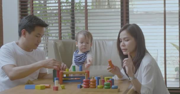 Mãe feliz, pai e pequeno menino asiático brincando com blocos de brinquedo de madeira em casa — Vídeo de Stock