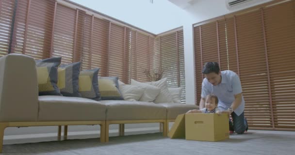 Щасливий батько і його син грають з картонною коробкою вдома разом — стокове відео