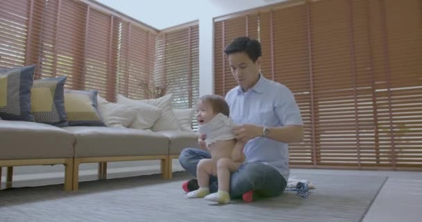 Young father at home with his little son changing his clothes. — Stock Video