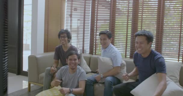 Gruppe asiatischer Mitbewohner schaut Sportwettkämpfe zu Hause im Fernsehen. — Stockvideo