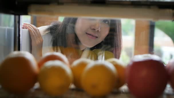 Ung asiatisk kvinna tittar genom bageri fönster och titta på kakor med ett leende — Stockvideo